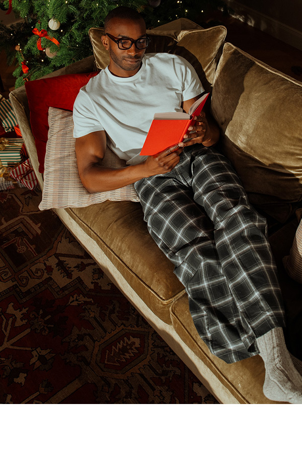 Mann auf dem Sofa liegend liest ein Buch